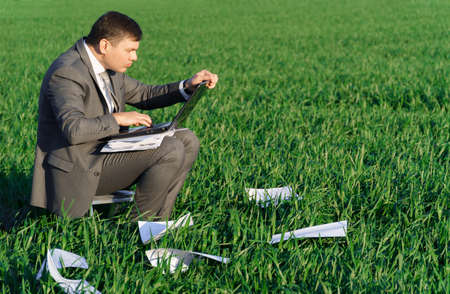 a businessman holds an office clock in a field with green grass - business and time conceptの写真素材