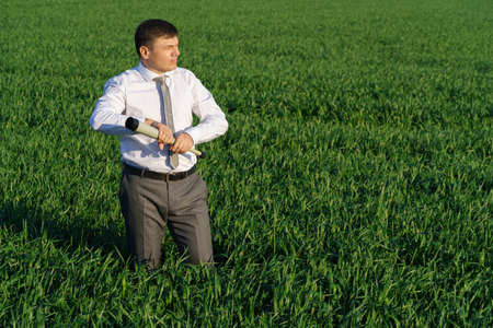 businessman holds an office red folder with documents in a green grass field - business conceptの写真素材