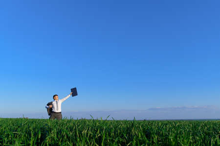 businessman holds a blackboard with an empty space and poses on a green grass field - business conceptの写真素材