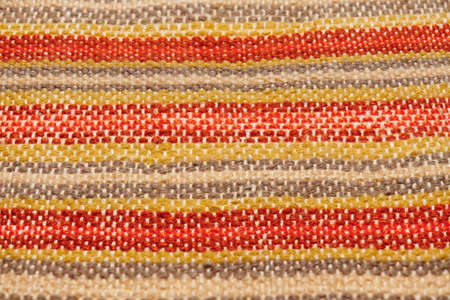 a small handmade rug or mat, woven from red and yellow wool threads, one object close-upの写真素材