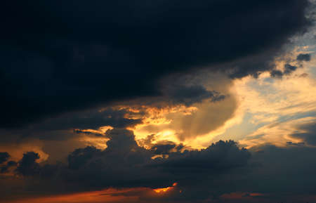 beautiful sunset sky, bright sun and dark silhouette of clouds as a background