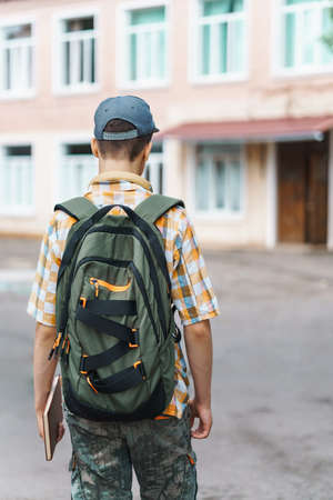 schoolboy poses in the backyard of the school, wearing a protective mask on his face from a coronavirus infection, education and back to school conceptの写真素材