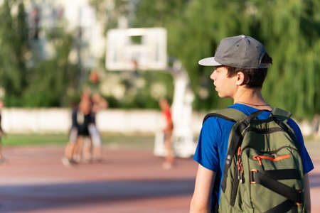 teenage boy exercising outdoors, sports ground in the yard, he hangs on the horizontal bar, raises his legs and shakes his abs, healthy lifestyleの写真素材