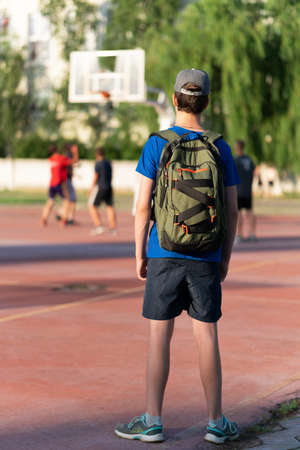 teenage boy exercising outdoors, sports ground in the yard, he hangs on the horizontal bar, raises his legs and shakes his abs, healthy lifestyleの写真素材