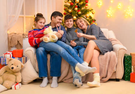 Winter holiday concept - Family sitting on a couch, interior with new year or christmas decoration....