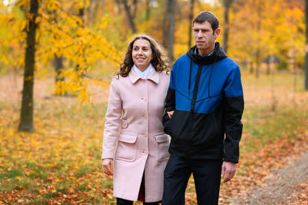 Romantic couple posing in an autumn park. Beautiful nature and trees with yellow leaves.