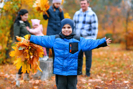 Portrait of a family with children in an autumn city park - happy people posing together near stump, beautiful nature with yellow leaves as background.の写真素材