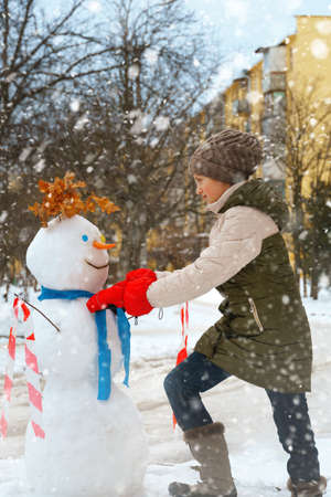 a girl plays snowballs outside, beautiful winter weather and white snow aroundの写真素材