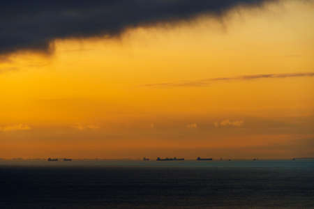 silhouettes of ships at sea, dramatic seascape with sunset sky, sunlight reflected from the waves