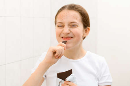 face of a shouting teenage girl, she looks at herself in the mirror and takes care of her skin, does...