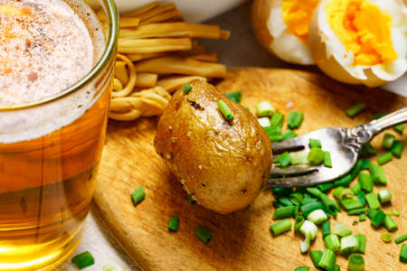 tasty food in rural style, - glass of beer, fried chicken meat and potatoes, garlic and green onions, cheese, boiled eggs and salt, cooked food on a white wooden boardsの写真素材