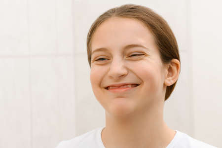face of a teenage girl, she looks at herself in the mirror and takes care of her skin, does cosmetic...