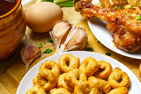 lunch in rural style, healthy food - glass of beer, fried chicken meat and unpeeled potatoes, eggs, green leek, salt and garlic, tasty cooked food on a white wooden boardsの写真素材