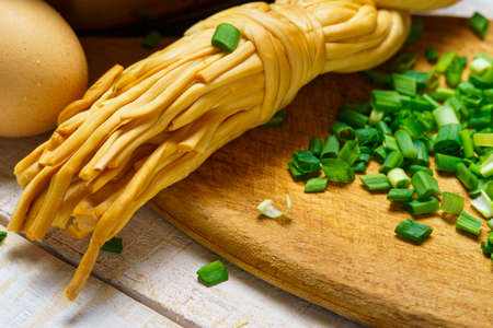 green onions, cheese and farm eggs, raw and cooked food in a rustic style on a background of white wooden boardsの写真素材