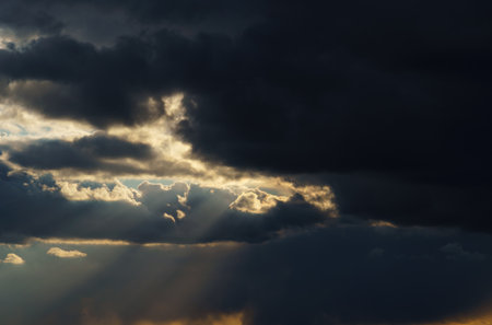 beautiful dramatic sky, bright sunlight and dark silhouette of clouds as background