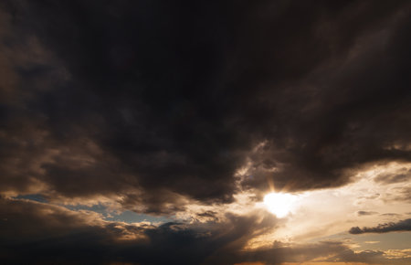 dark dramatic sky, bright sunlight and black silhouette of clouds as backgroundの写真素材