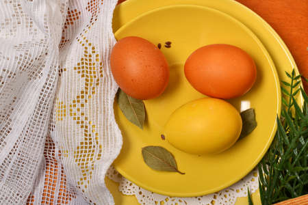 easter eggs in a yellow dish and other decoration on a red wooden background, holiday still life