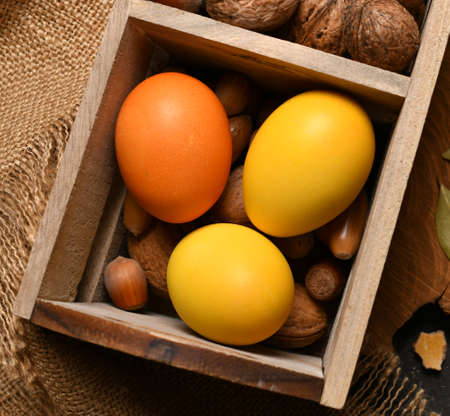 easter holiday still life and decorations, easter eggs in a box with nuts on a dark wooden...