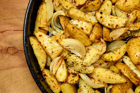 roasted potatoes in a frying pan, cooked food, delicious crust, one object on a wooden backgroundの写真素材