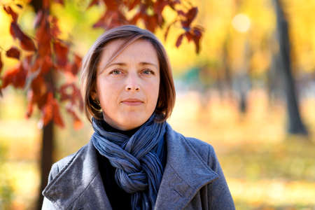 portrait of a beautiful woman posing in a city park in autumn, bright sunny day, colorful yellow leavesの写真素材