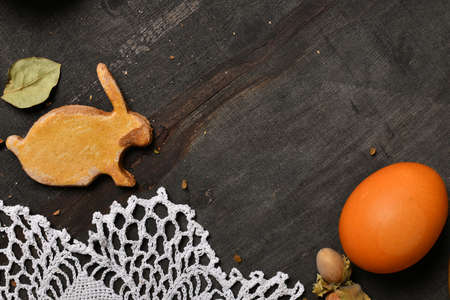 easter holiday still life and decorations, easter egg, cookie in the shape of rabbit on dark wooden background, blank space for textの写真素材