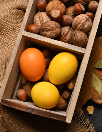 easter holiday still life and decorations, easter eggs in a box with nuts on a dark wooden backgroundの写真素材