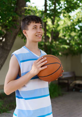teenage boy playing basketball in the backyard, outdoor activities on summer vacationの写真素材