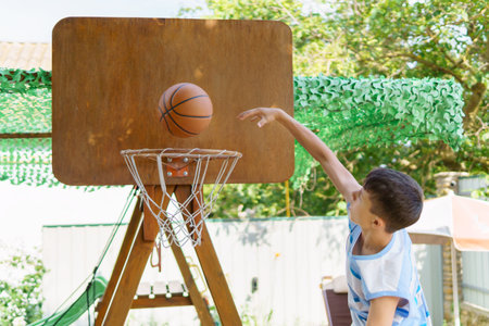 teenage boy playing basketball in the backyard, outdoor activities on summer vacation