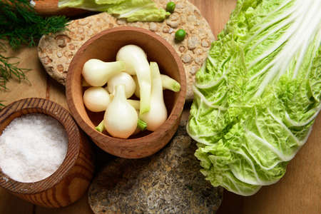 vegetables on a wooden kitchen board, cabbage, onions and peas on a wood background, concept of fresh and healthy food, still lifeの写真素材