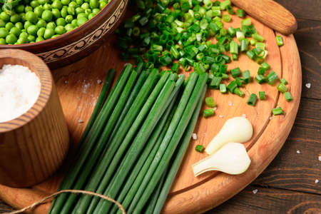 green sweet peas on a dark wooden background, onion, salt, still life, concept of fresh and healthy...