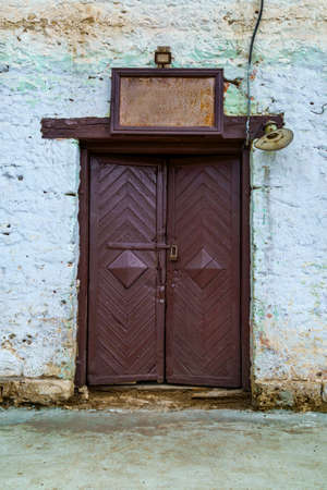 a vintage door in an old farmhouse or barn, a rusty signboard with an empty space for text and lantern, wall painted with white blue paintの写真素材
