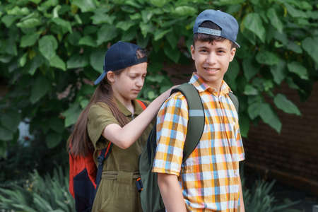 portrait of students in a city park, teenage schoolchildren a boy and a girl are standing on the path and discussing lessons, reading a book and talkingの写真素材