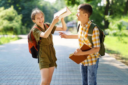 portrait of students in a city park, teenage schoolchildren a boy and a girl sitting on a bench, resting and eating applesの写真素材