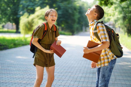 portrait of students in a city park, teenage schoolchildren a boy and a girl sitting on a bench, resting and eating applesの写真素材