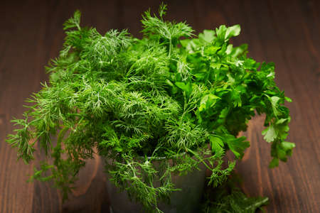 a bunch of green dill and parsley in an iron bucket, dark wooden background, concept of fresh vegetables and healthy foodの写真素材