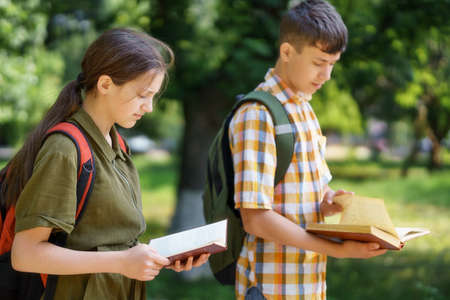portrait of students in a city park, teenage schoolchildren a boy and a girl are standing on the...