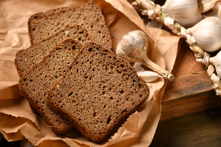 still life of food in a rural style on a dark wood background, rye bread and garlic, concept of...