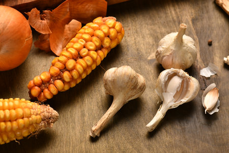 still life of food in a rural style on a dark wood background, corn and garlic, concept of fresh vegetables and healthy foodの写真素材