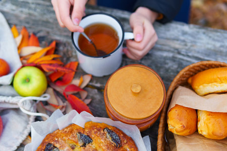 picnic in the autumn season, food on a wooden table, hot tea, pastries and sandwiches