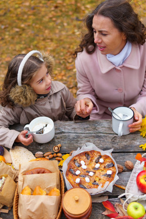 picnic in the autumn season, food on a wooden table, hot tea, pastries and sandwichesの写真素材