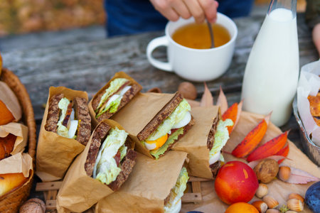 picnic in the autumn season, food on a wooden table, hot tea, pastries and sandwichesの写真素材