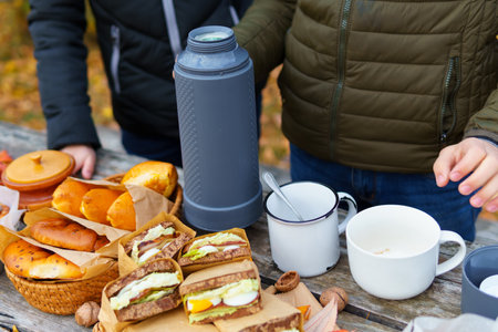 picnic in the autumn season, food on a wooden table, hot tea, pastries and sandwichesの写真素材