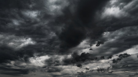 dark dramatic sky with black stormy clouds before rain or snow as abstract background, extreme weather, the sun shines through the clouds, high contrast photoの写真素材