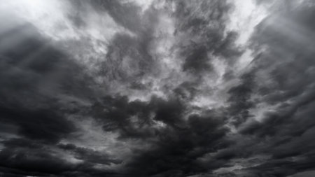 dark dramatic sky with black stormy clouds before rain or snow as abstract background, extreme weather, the sun shines through the clouds, high contrast photoの写真素材