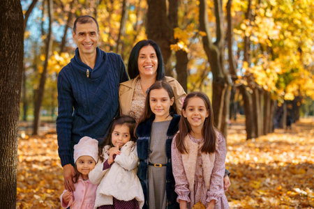 portrait of big family in autumn city park, children and parents, happy people posing together, beautiful nature, bright sunny day and yellow leavesの写真素材