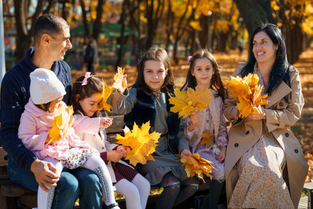 portrait of big family with children in an autumn city park, happy people sitting together on a...