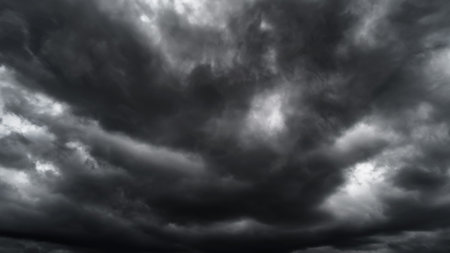 dark dramatic sky with black stormy clouds before rain or snow as abstract background, extreme weather, the sun shines through the clouds, high contrast photoの写真素材