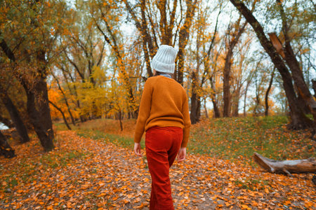 a young teenage girl walks through the autumn forest, walks through a glade and enjoys the beautiful...