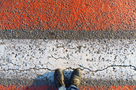 top view of the pedestrian crossing road markings and feet, red and white lines on the asphalt as a...