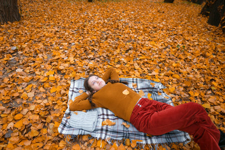 a young teenage girl is lying in a glade by the river bank in an autumn forest, enjoying the...